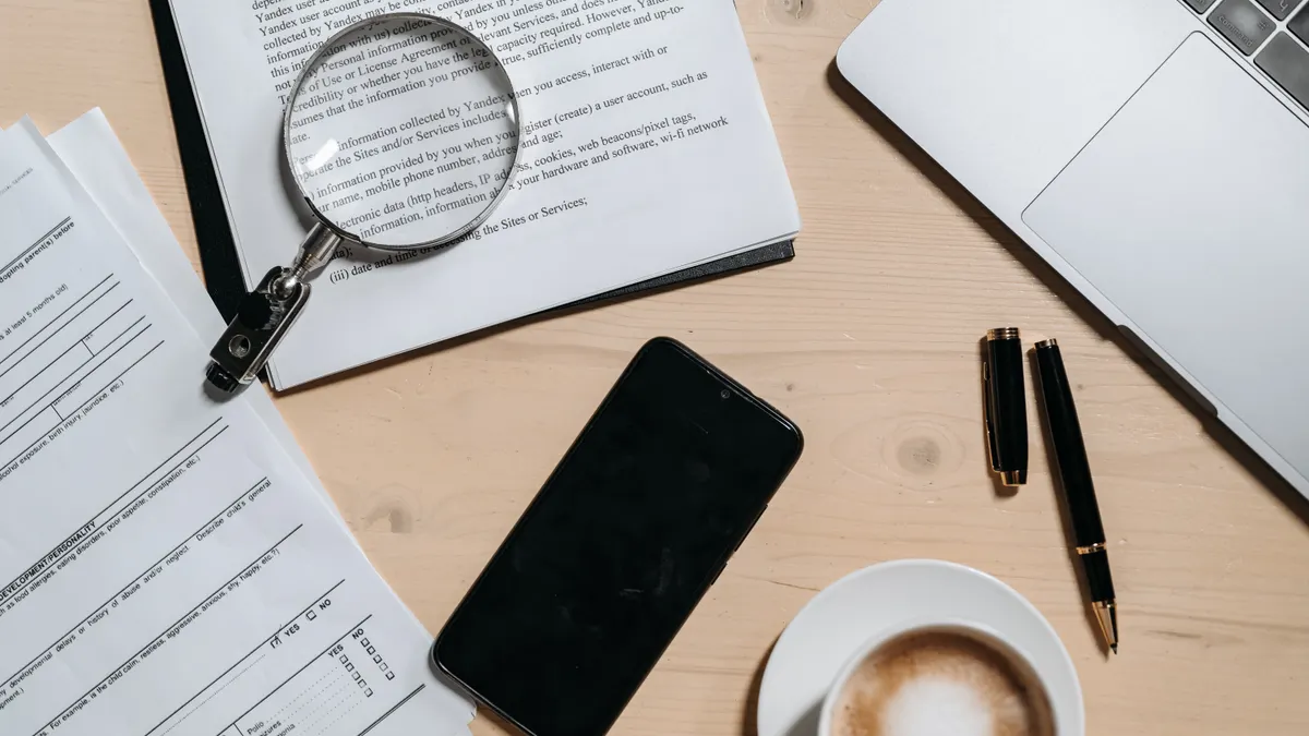AI article writer plagiarism check: how to review originality before publishing Magnifying glass over paperwork on a desk with a laptop