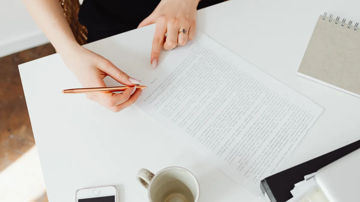 Hands editing a printed document at a bright desk